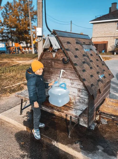 Сын набирает воду в сельской колонке